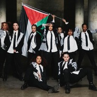 Kehlani terlihat memakai kemeja putih dan dasi hitam, dipadu jas panjang dengan aksen keffiyeh, yang diaplikasikan di area bahu dan bagian bawah jas. Foto: Instagram/@kehlani @_miazaki_