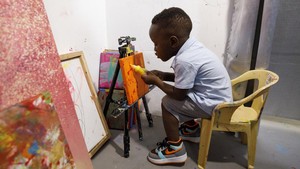 Seniman mungil ini tinggal di negara Ghana di Afrika Barat. Dia melukis di Arts and Cocktails Studio, yang didirikan oleh ibunya. Dia memberinya kebebasan penuh untuk menciptakan apa pun yang dia inginkan, dalam warna apa pun yang menginspirasinya.