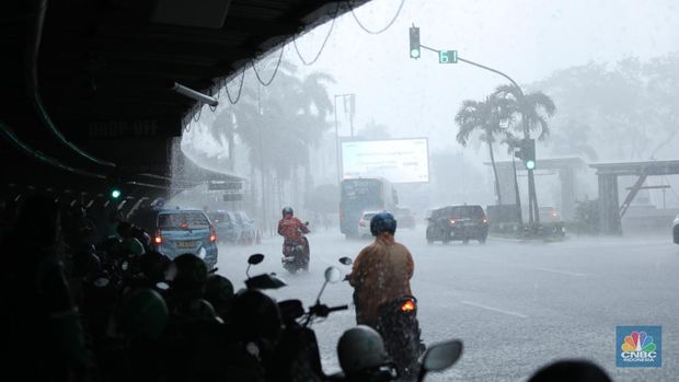 Sejumlah pengendara berteduh saat hujan deras dan angin kencang di kawasan Sudirman, Jakarta, Selasa (4/6/2024). (CNBC Indonesia/Tri Susilo)