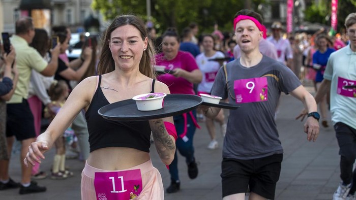 Restaurant waiters participate in carry bowls of pink soup for 600 meters run competition through the town in Vilnius, Lithuania, Saturday, June 1, 2024. The iconic cold pink soup Saltibarsciai is a traditional Lithuanian cold beet soup usually served in summer and usually made with buttermilk, sour cream, hard-cooked eggs, cucumbers, dill and pickled beetroot which gives the cold soup its bright pink colour and served with boiled potatoes. Pink Soup Fest will officially kick-start the summer season in the city. (AP Photo/Mindaugas Kulbis)