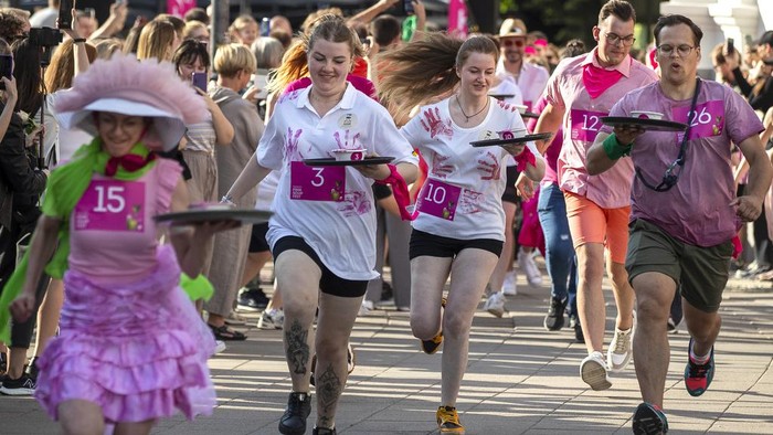 Restaurant waiters participate in carry bowls of pink soup for 600 meters run competition through the town in Vilnius, Lithuania, Saturday, June 1, 2024. The iconic cold pink soup Saltibarsciai is a traditional Lithuanian cold beet soup usually served in summer and usually made with buttermilk, sour cream, hard-cooked eggs, cucumbers, dill and pickled beetroot which gives the cold soup its bright pink colour and served with boiled potatoes. Pink Soup Fest will officially kick-start the summer season in the city. (AP Photo/Mindaugas Kulbis)