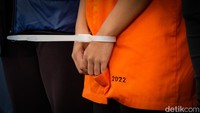 R memakai masker dan tangan diikat kabel ties. R tengah menjalani pemeriksaan mental.