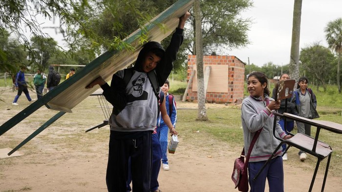 Municipal worker Gloria Soilan teaches seventh graders from the New Asuncion school, outside their school building in Presidente Hayes in Paraguay's Chaco region, Monday, June 3, 2024. Due to not enough classrooms, students have been attending classes outside for the past three years with instruction from a municipal worker. (AP Photo/Jorge Saenz)