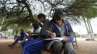 Para siswa itu belajar di luar gedung karena sekolah mereka kekurangan ruang kelas.  