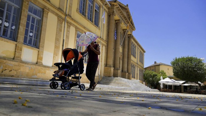 Siprus Dilanda Gelombang Panas, Suhu Mencapai 42 Derajat Celsius A woman walks outside from a souvenir shop as she protects herself from the sun with an umbrella during a hot day in central capital Nicosia, Cyprus, on Tuesday, June 4, 2024. The Meteorological Department said the heatwave's highest temperatures in this days they're expected to reach 42 degrees Celsius (107,6 Fahrenheit) inland and 32 degrees (89,6 Fahrenheit) in the island's main Troodos mountain range. (AP Photo/Petros Karadjias)