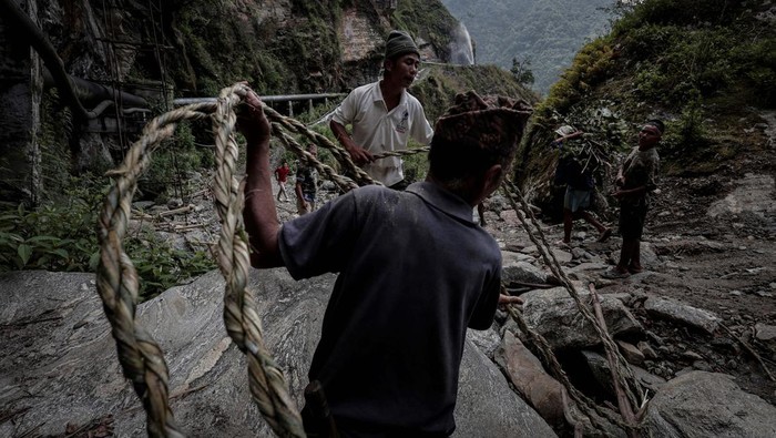 Villagers carry Bashanta Gurung, 18, towards a safe location after he collapsed after getting stung by wild bees during honey hunting near Taap in Lamjung, Nepal, May 29, 2024. For generations, the Gurung community in Taap, about 175 km (110 miles) west of the capital, Kathmandu, and other villages in the nearby districts of Lamjung and Kaski, have scoured the steep Himalayan cliffs for honey. Now the generations-old craft is increasingly under threat as some experts say rising temperatures brought by climate change disrupt the growth of bees, the availability of their food and even pollination of plants.        REUTERS/Navesh Chitrakar           SEARCH 