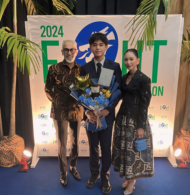 Bunga Zainal dan suami bulenya, Sukhdev Singh, menghadiri acara wisuda putranya yang lulus dari Jakarta Intercultural School. Bunga memilih mengenakan setelan hitam dengan rok batik yang tampak rapi dan anggun. Foto: Instagram