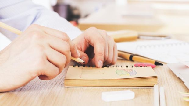 Watercolor paint canva and brushes used to create new paintings. Hand holding a brush. Starting a bullet journal in a dot notebook. New beginnings. Art and creativity concept.