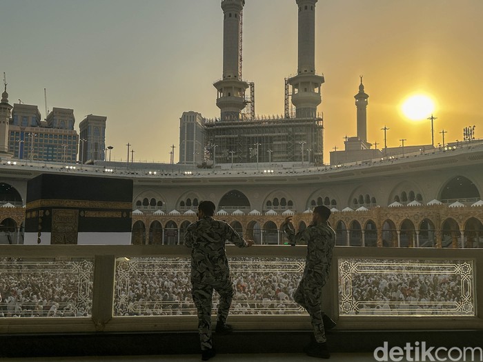 Dua orang petugas keamanan berjaga di Masjidil Haram saat mahatari hampir terbenam di Makkah, Arab Saudi.