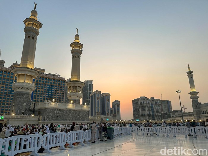 Dua orang petugas keamanan berjaga di Masjidil Haram saat mahatari hampir terbenam di Makkah, Arab Saudi.