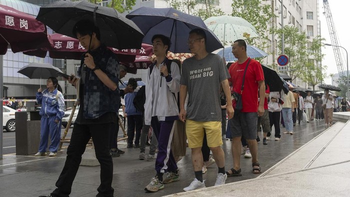Di tengah hujan yang turun di Beijing, China, para orang tua tetap mengantarkan hingga menunggu anaknya untuk mengikuti ujian masuk perguruan nasional. Ini potretnya.