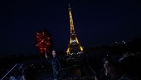 Warga berfoto dengan latar belakang Menara Eiffel.