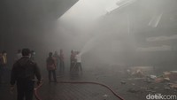 Petugas dari Dinas Pemadam Kebakaran (Damkar) Denpasar berjibaku memadamkan api yang membakar gudang LPG dan pipa paralon di tengah kepungan asap. Air diseprotkan ke areal gudang yang terbakar. (Ahmad Firizqi Irwan/detikBali)