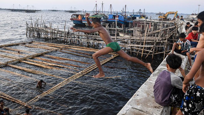 Sejumlah anak mandi di laut kawasan Cilincing, Jakarta Utara. Dengan wajah ceria, mereka berlomba-lomba melompat dari tanggul ke laut.