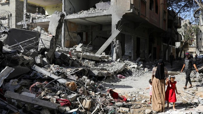 People walk among debris, aftermath of Israeli strikes at the area, where Israeli hostages were rescued on Saturday, as Palestinian death toll rises to 274, amid the Israel-Hamas conflict, in Nuseirat refugee camp in the central Gaza Strip, June 9, 2024. REUTERS/Abed Khaled