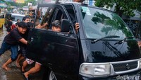 Warga mendorong sejumlah kendaraan yang memaksa menerobos banjir.