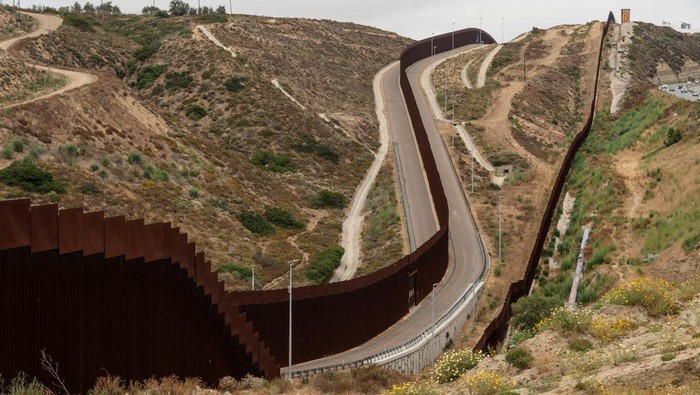 Asylum-seeking migrants walk toward main road to be transported at a staging area, after U.S. President Joe Biden announced a sweeping border security enforcement effort, in Jacumba Hot Springs, California, U.S. June 10, 2024. REUTERS/Go Nakamura
