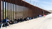 Migran pencari suaka beristirahat di tempat teduh di dekat tembok perbatasan Meksiko-AS di Tijuana, Meksiko, Senin (10/6/2024).  