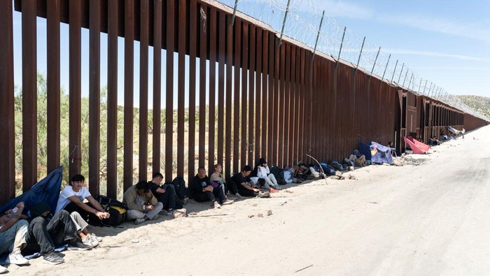 Joe Biden Tutup Sementara Perbatasan AS-Meksiko untuk Cegah Migran Ilegal Asylum-seeking migrants walk toward main road to be transported at a staging area, after U.S. President Joe Biden announced a sweeping border security enforcement effort, in Jacumba Hot Springs, California, U.S. June 10, 2024. REUTERS/Go Nakamura