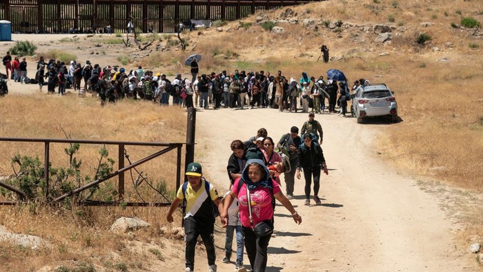 Asylum-seeking migrants walk toward main road to be transported at a staging area, after U.S. President Joe Biden announced a sweeping border security enforcement effort, in Jacumba Hot Springs, California, U.S. June 10, 2024. REUTERS/Go Nakamura