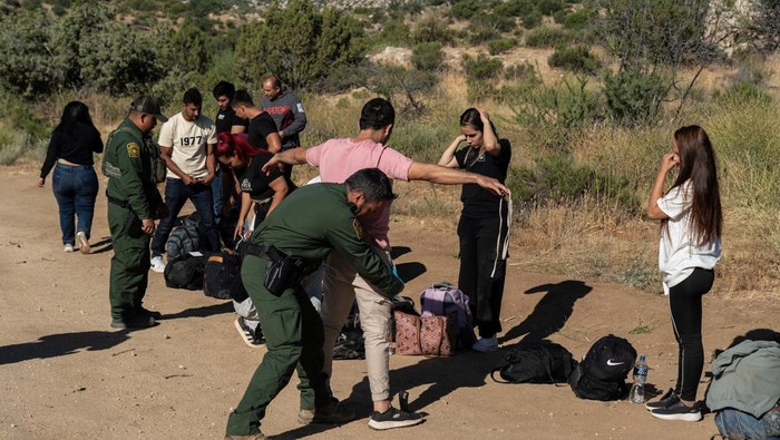 Joe Biden Tutup Sementara Perbatasan AS-Meksiko untuk Cegah Migran Ilegal Asylum-seeking migrants walk toward main road to be transported at a staging area, after U.S. President Joe Biden announced a sweeping border security enforcement effort, in Jacumba Hot Springs, California, U.S. June 10, 2024. REUTERS/Go Nakamura