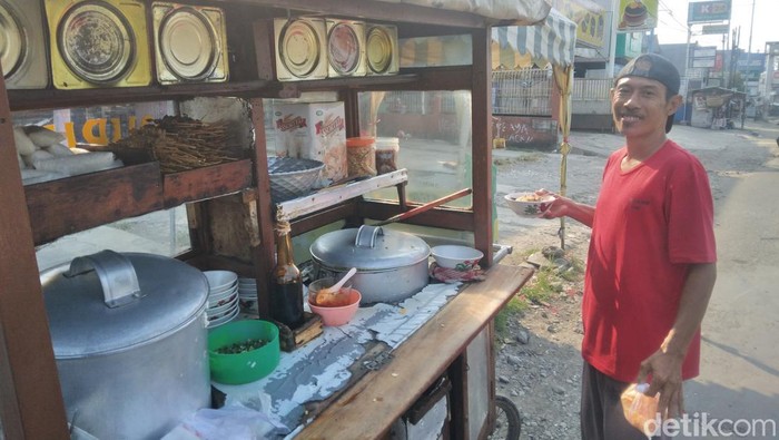 Mang Ocoy di depan gerobak bubur miliknya.