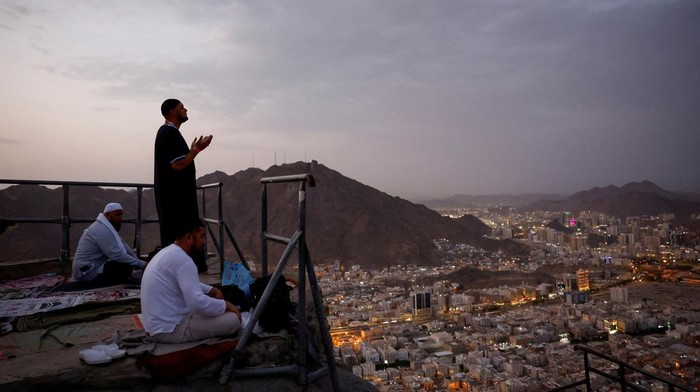 Potret Jemaah Haji Lantunkan Doa di Jabal Nur Muslim pilgrims pray at Mount Al-Noor, where Muslims believe Prophet Mohammad received the first words of the Koran through Gabriel in the Hira cave, ahead of the annual haj pilgrimage in the holy city of Mecca, Saudi Arabia, June 11, 2024. REUTERS/Mohammed Torokman