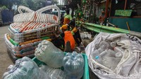 Para petugas membuat perahu memanfaatkan sekitar 1.500 botol plastik bekas yang terjaring di sungai yang melintasi Kwitang.
