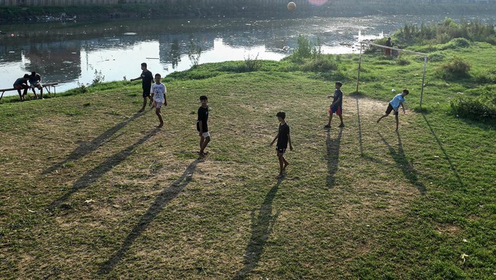 Sejumlah anak bermain bola di bantaran Kanal Banjir Barat, Jakarta, Senin (10/6/2024). Alih fungsi lahan yang dijadikan kawasan hunian, pusat perbelanjaan, dan gedung perkantoran mengakibatkan semakin berkurangnya lahan bermain untuk anak di Jakarta. ANTARA FOTO/Muhammad Adimaja/tom.