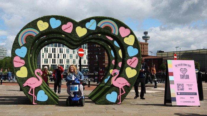 People walk near banners displaying the name of musician Taylor Swift as part of the Taylor Town Trail in anticipation of her arrival, as she will perform three concerts at Anfield Stadium, in Liverpool, Britain June 10, 2024. REUTERS/Molly Darlington