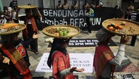 Mereka membawa tampah dan hasil kebun dalam aksi tersebut.