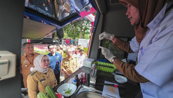 Pj Wali Kota Jambi Sri Purwaningsih (kedua kiri) menyaksikan petugas menguji kandungan pestisida tanaman sayur di dalam mobil laboratorium mobile Pemerintah Kota Jambi saat peluncurannya di Kota Baru, Jambi, Selasa (11/6/2024). Pemerintah Kota Jambi meluncurkan satu unit mobil laboratorium mobile yang dilengkapi petugas dan peralatan uji kandungan pangan yang ditugaskan hingga ke pelosok untuk menjamin peredaran pangan yang aman dan sehat di daerah itu secara gratis. ANTARA FOTO/Wahdi Septiawan/foc.