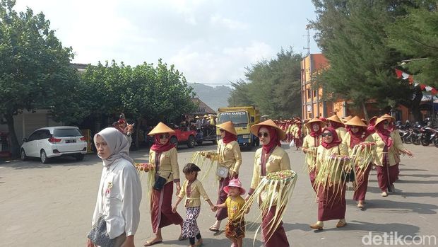 Warga berpakaian adat Jawa saat mengarak uba rampe berupa hasil bumi dari Pantai Parangtritis ke Pantai Parangkusumo, Kretek, Bantul, Selasa (11/6/2024).