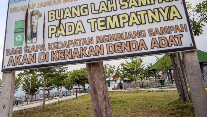 Warga berjalan di dekat papan peringatan membuang sampah di Taman Huntap Duyu, Palu, Sulawesi Tengah, Selasa (11/6/2024). Pemerintah kelurahan bersama lembaga adat setempat mengenakan 'givu' atau denda adat bagi pengunjung yang kedapatan membuang sampah secara sembarangan di kawasan itu berupa dua ekor kambing sebagai upaya edukasi dan menjaga kebersihan lingkungan. ANTARA FOTO/Basri Marzuki/nym.