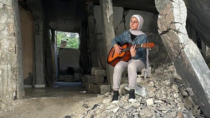 ISRAEL-PALESTINIANS/GAZA-MUSIC A Palestinian medical student, Rahaf Nasser plays music amid the ongoing conflict between Israel and Hamas, in Deir Al-Balah, in the central Gaza Strip June 5, 2024. REUTERS/Moaz Abu Taha