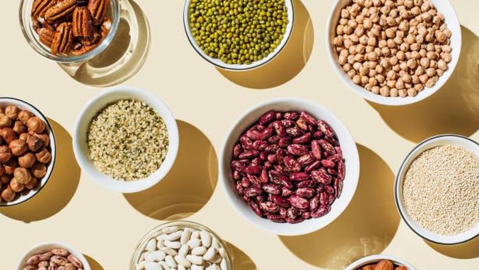 Various kinds of vegan protein sources on beige background. Set of food supplements. Gluten free cereals as ground hemp seeds, quinoa. Nuts and legumes (green mung beans, chick-pea, red lentil, kidney bean, almonds, hazelnuts). Flat lay, top view