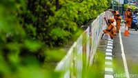 Petugas Penanganan Prasarana dan Sarana Umum (PPSU) Kelurahan Kebayoran Lama Utara alias pasukan oranye mengecat mural di dinding Underpass Arteri Pondok Indah, Jakarta, Rabu (12/6/2024).