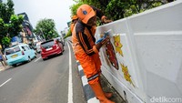 Pasukan oranye mengecat di sepanjang dinding underpass.   