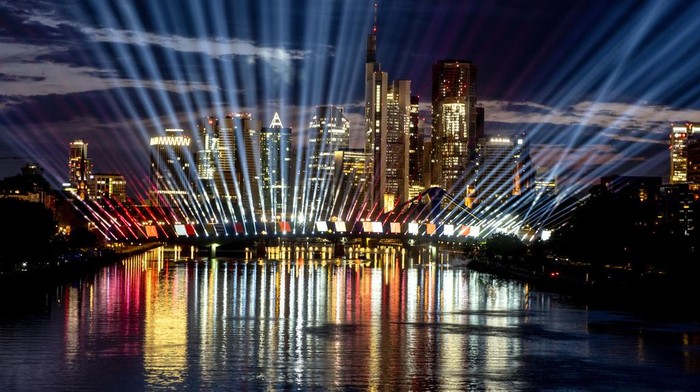 A test run of a light show illuminates the sky and the river Main in Frankfurt, Germany, late Tuesday, June 11, 2024. The show is part of the city's entertainment program on occasion of the Euro 2024 soccer tournament and will take place every evening during the tournament. (AP Photo/Michael Probst)