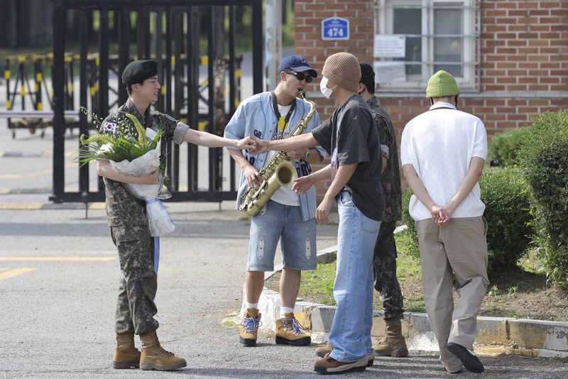 K-pop band BTS's member Jin, left, is greeted by other members j-hope, center, and RM, right, after being discharged from a mandatory military service outside of an army base in Yeoncheon, South Korea, Wednesday, June 12, 2024. (Im Byung-shik/Yonhap via AP)