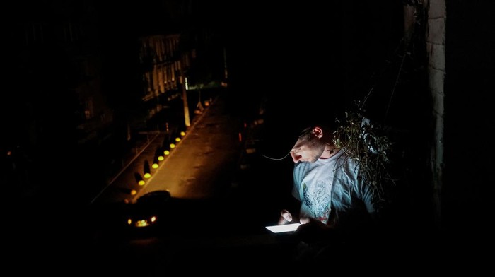 Ukrainian artist Yevhen Klymenko, a 29-year-old, uses a phone on his balcony during a blackout, amid Russia's attack on Ukraine, in Kyiv, Ukraine, June 5, 2024. REUTERS/Alina Smutko