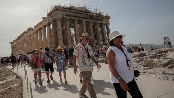 Tourists visit the Parthenon temple atop the Acropolis hill archaeological site before it closes due to a heatwave hitting Athens, Greece, June 13, 2024. REUTERS/Louiza Vradi