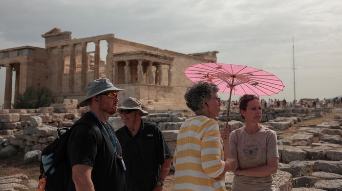 Tourists visit the Parthenon temple atop the Acropolis hill archaeological site before it closes due to a heatwave hitting Athens, Greece, June 13, 2024. REUTERS/Louiza Vradi