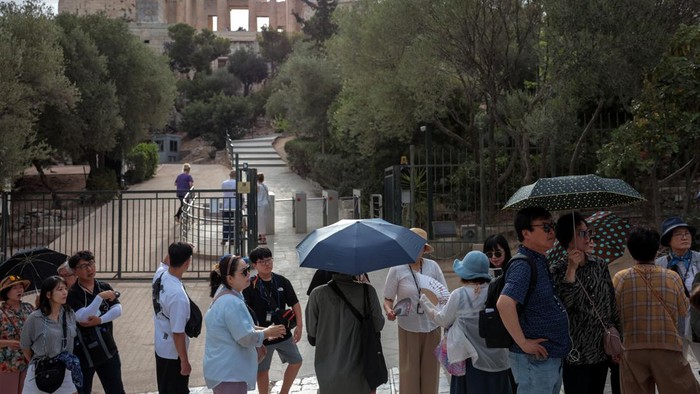 Tourists visit the Parthenon temple atop the Acropolis hill archaeological site before it closes due to a heatwave hitting Athens, Greece, June 13, 2024. REUTERS/Louiza Vradi