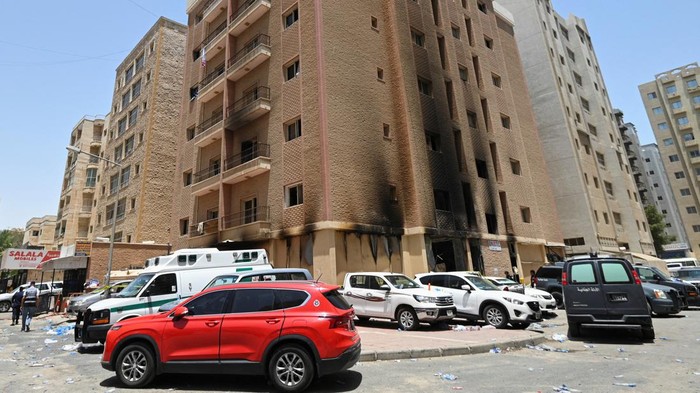 Horor Kebakaran Gedung Pekerja Asing di Kuwait, 49 Orang Tewas Kuwaiti police officers are seen in front of a burnt building following a deadly fire, in Mangaf, southern Kuwait, June 12, 2024. REUTERS/Stringer