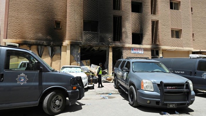 Kuwaiti police officers are seen in front of a burnt building following a deadly fire, in Mangaf, southern Kuwait, June 12, 2024. REUTERS/Stringer