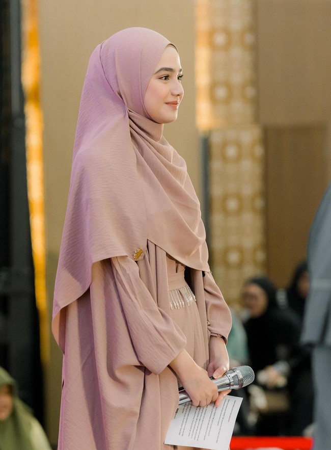 Wanita kelahiran 13 Juli 2000 ini mengenakan abaya dengan inner yang memiliki detail taburan beads sebagai belt. Syifa mengenakan hijab pashmina yang dibentuk menutupi dada dan jarum pentul di bagian bawah telinga. Foto: Dok. Instagram @syifahadju.