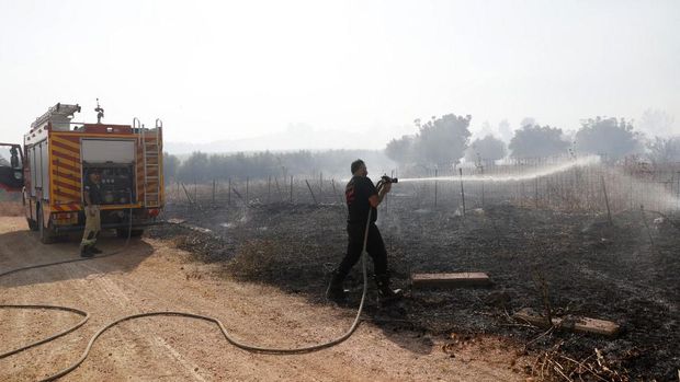 Tentara Israel berupaya memadamkan api yang membakar lahan hutan mereka setelah serangan rudal Hizbullah di pinggir jalan dekat perbatasan Israel dengan Lebanon, di Israel. (Photo by Jalaa MAREY / AFP)