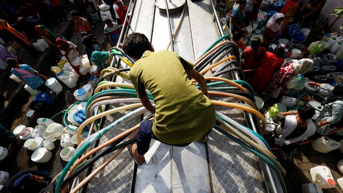ASIA-WEATHER/INDIA-HEATWAVE Residents use pipes to fill their containers with drinking water from a water tanker during a hot day in New Delhi, India, June 13, 2024. REUTERS/Priyanshu Singh