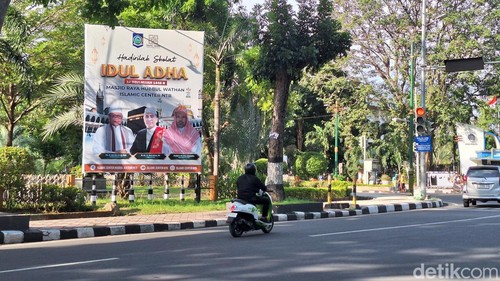 Beberapa pengendara melintas di depan spanduk informasi salat Idul Adha 2024 di Mataram. (Nathea Citra /detikBali)